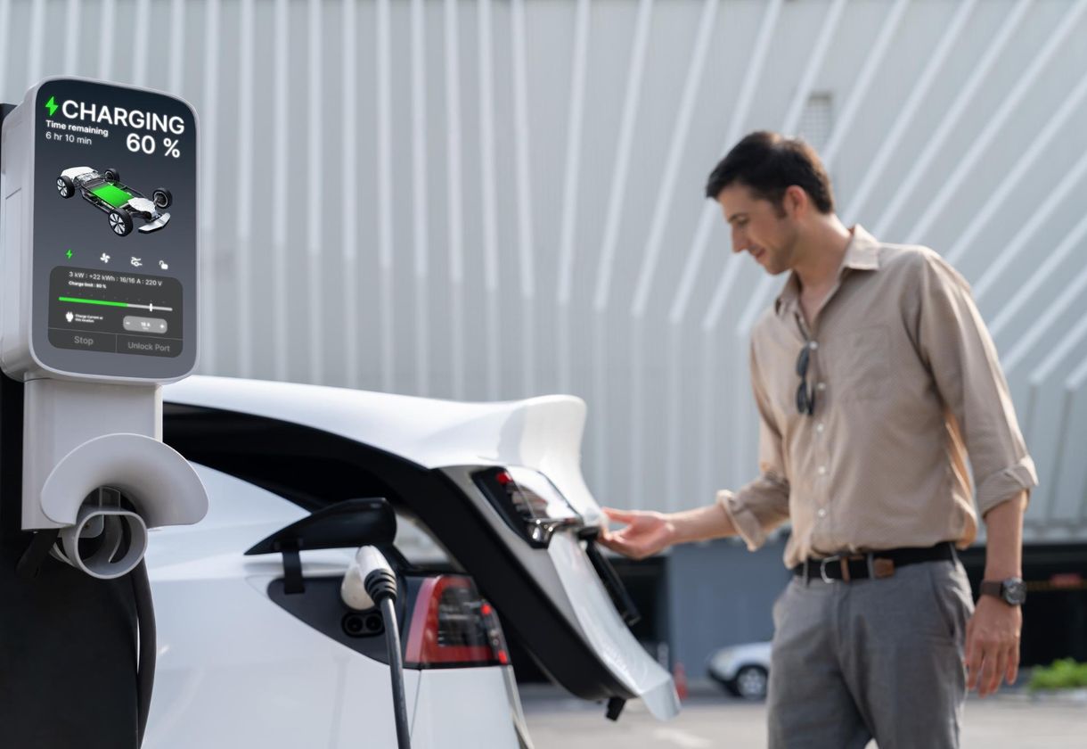 Man plugging in electric vehicle at charging station.